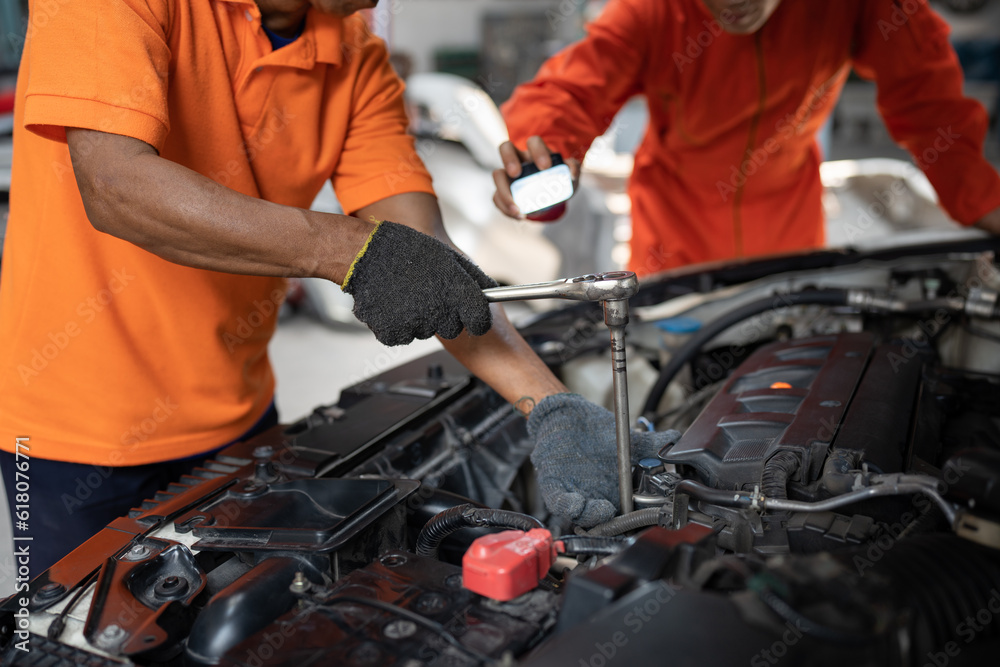 Asia mechanic man examining and maintenance to engine a vehicle car hood with car lift background at car service Asia mechanic man examining and maintenance to engine a vehicle car hood with car lift background at car service