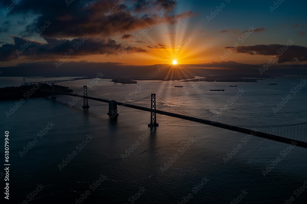 the sun is setting over the ocean with the bridge going into the distance