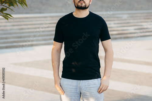 Young stylish bearded man in a black T-shirt and sunglasses. Street photo