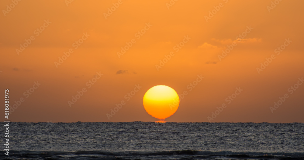 magicl sunrise with a burning and torn orange sun at the horizon from the red sea in egypt panorama