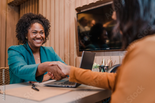 Brazilian woman bank manager in Brazil smiling shaking hands with her client after signing a loan agreement