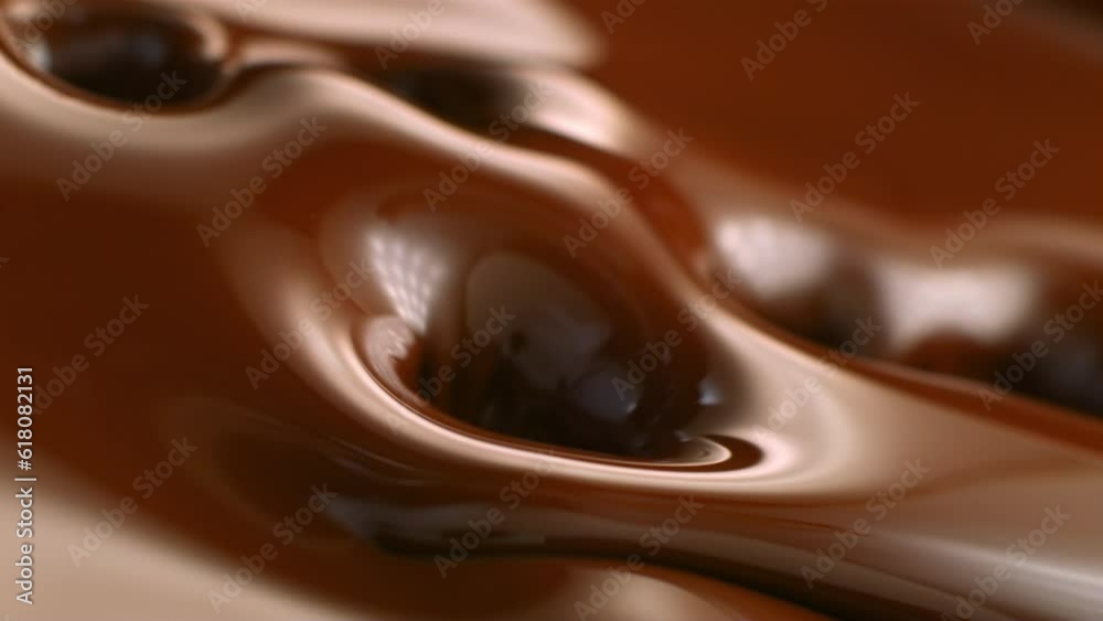 Slow motion of small pieces of nuts falling into the brown melted chocolate Slow motion of small pieces of nuts falling into the brown melted chocolate