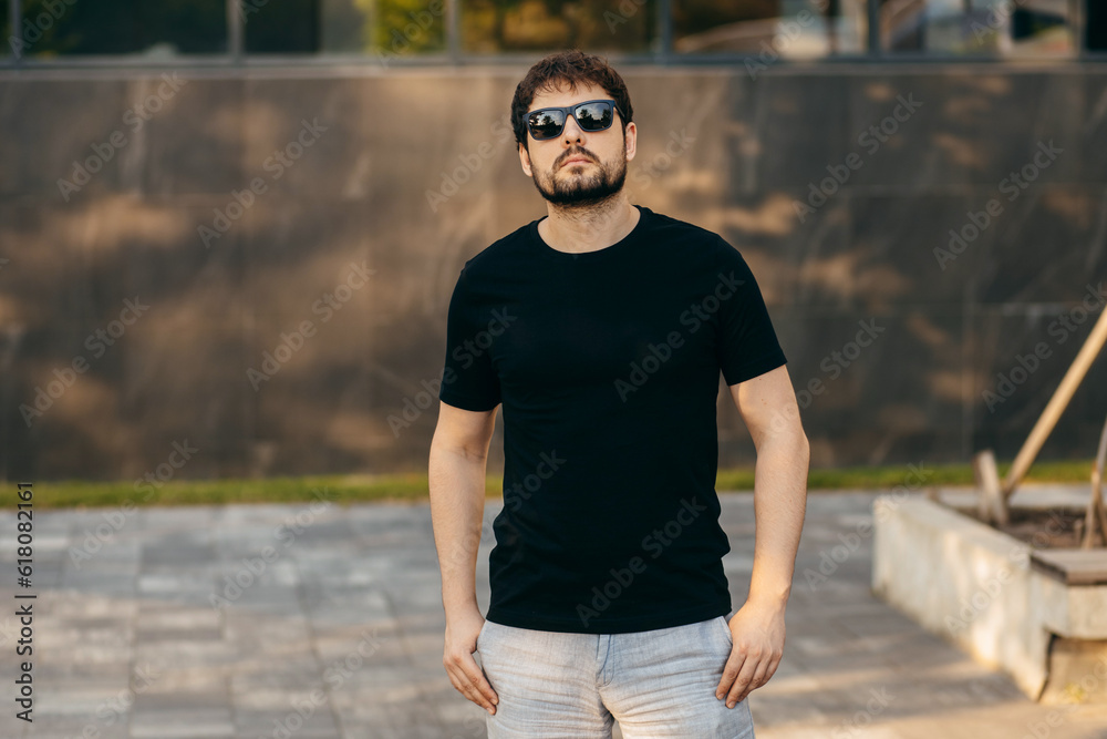 Young stylish bearded man in a black T-shirt and sunglasses. Street photo Young stylish bearded man in a black T-shirt and sunglasses. Street photo