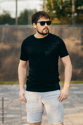 Young stylish bearded man in a black T-shirt and sunglasses. Street photo