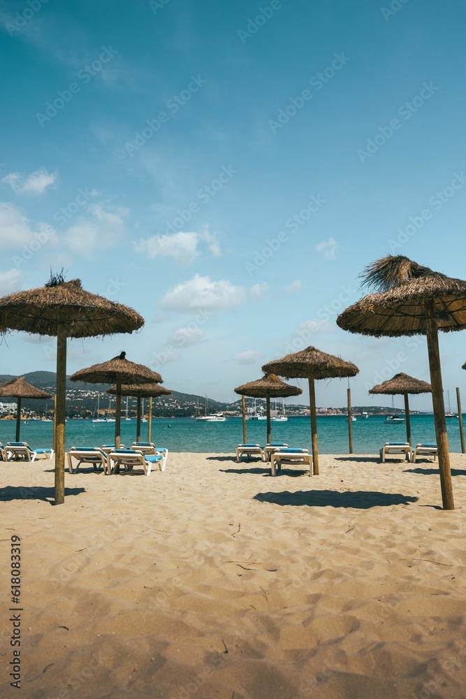 Picturesque beach scene with a variety of beach chairs and umbrellas scattered on the sand Picturesque beach scene with a variety of beach chairs and umbrellas scattered on the sand