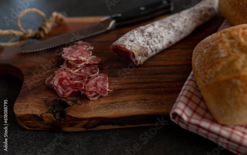 Sliced spanish salami, fuetec from iberico pork on a wooden board with knife