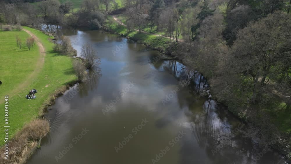 Aerial of a narrow water canal passing alongside the green fields and trees Aerial of a narrow water canal passing alongside the green fields and trees