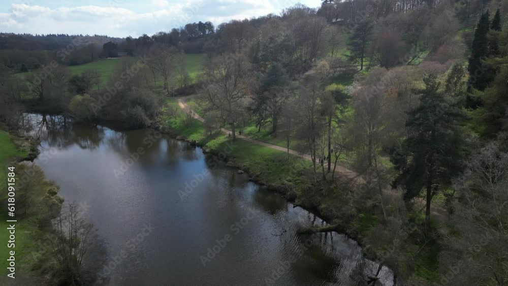 Aerial of a narrow water canal passing alongside the green fields and trees