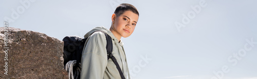 Bild auf Leinwand Young short haired and tattooed female tourist in casual clothes with backpack l