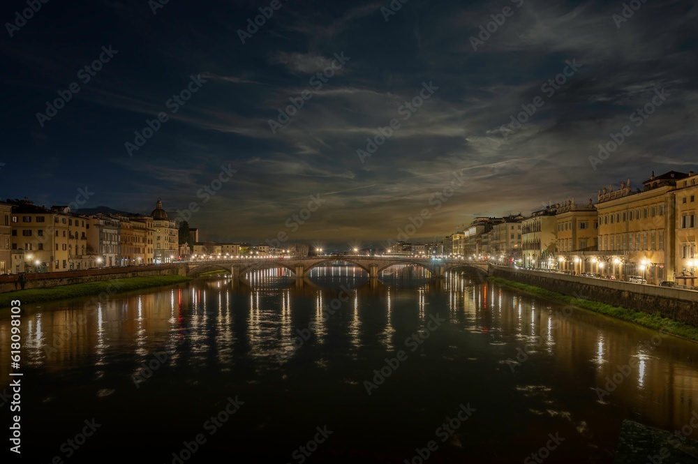 Tranquil scene featuring a a bridge over the tranquil river in Florence, Italy at night