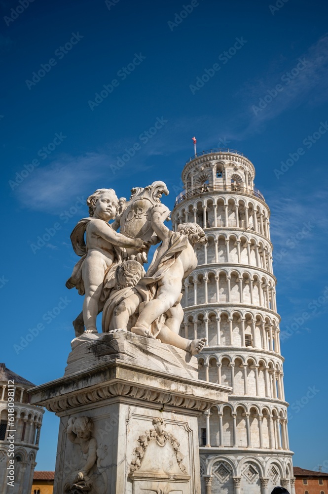 Ornate marble sculpture situated in front of the iconic Leaning Tower of Pisa in Italy