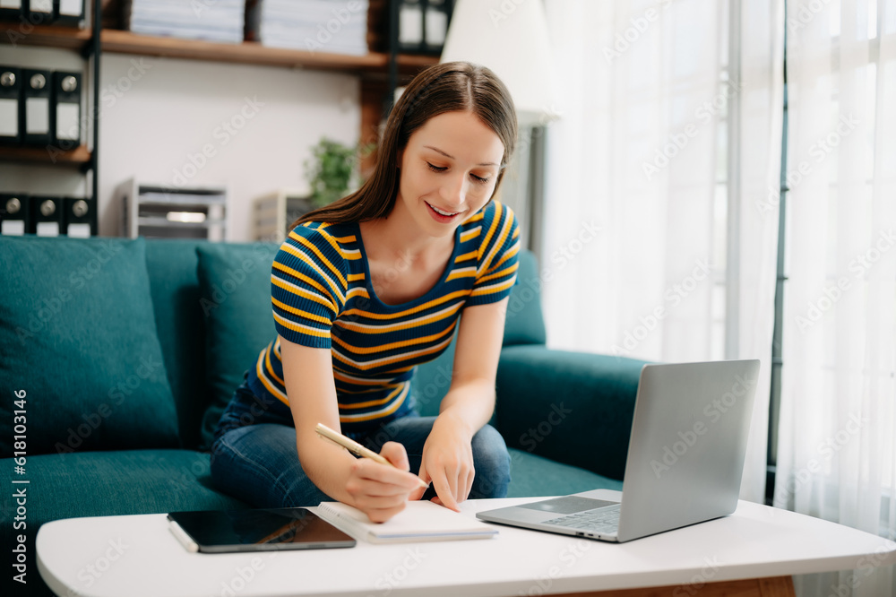 Confident Caucasian woman with a smile standing holding notepad and tablet in living room on the sofa at office Confident Caucasian woman with a smile standing holding notepad and tablet in living room on the sofa at office