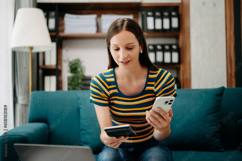 Confident Caucasian woman with a smile standing holding notepad and tablet in living room on the sofa at office Confident Caucasian woman with a smile standing holding notepad and tablet in living room on the sofa at office