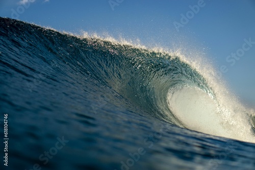Majestic, powerful wave is rolling forward the shore under a blue sky