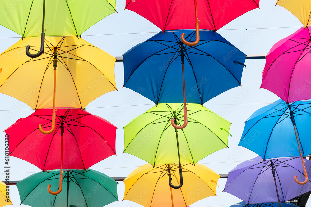 Lots of umbrellas coloring the sky in the city,Colorful yellow red blue white green pink color fabric umbrella with blue sky cloud background