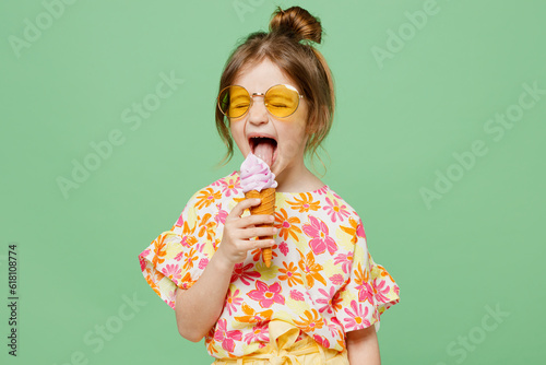 Obraz na plátne Little cute child kid girl 6-7 years old wearing casual clothes sunglasses eat icecream have fun isolated on plain pastel green background studio portrait