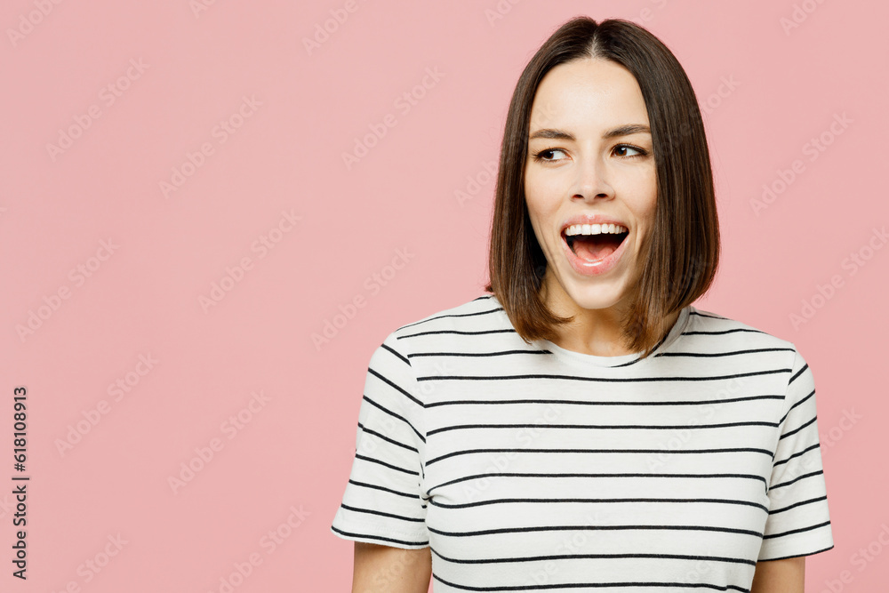 Young surprised shocked happy fun caucasian woman she wears casual clothes t-shirt look aside on area mock up laugh isolated on plain pastel light pink background studio portrait. Lifestyle concept. Young surprised shocked happy fun caucasian woman she wears casual clothes t-shirt look aside on area mock up laugh isolated on plain pastel light pink background studio portrait. Lifestyle concept.
