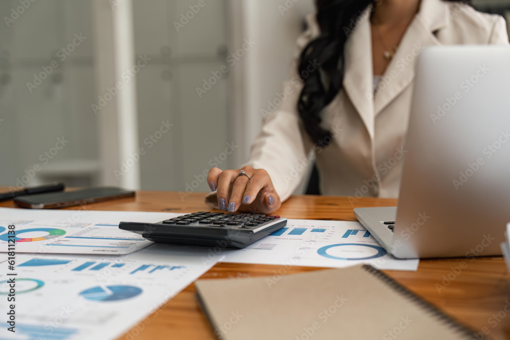 Close-up of businesswoman hands using a calculator to check company finances and earnings and budget. Business woman calculating monthly expenses, managing budget, papers, loan documents, invoices - obrazy, fototapety, plakaty 