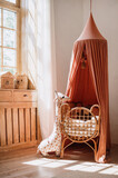 Woven cot with red textile baldachin in kids room