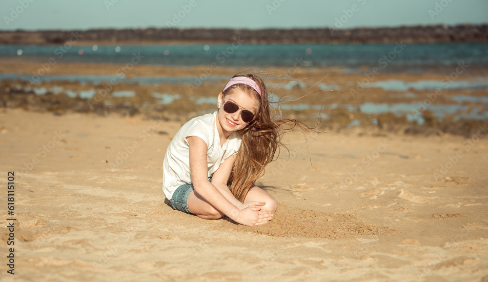 Fototapeta premium little girl in a hat on a sandy beach