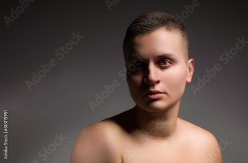 portrait of young woman with short hair and bare shoulder on grey background © Igor Borodin