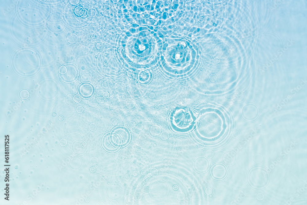 abstract fresh transparent blue water surface from above with rain drop circles in sunlight, liquid texture background concept for cosmetic moisturizer and beauty products with space for text