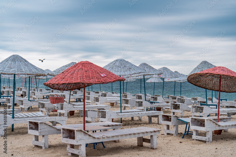Sun bed chairs with matress and straw beach umbrellas on beach. Blue hour time background by the sea.. Sun bed chairs with matress and straw beach umbrellas on beach. Blue hour time background by the sea..
