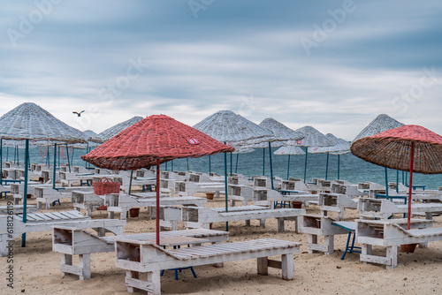 Sun bed chairs with matress and straw beach umbrellas on beach. Blue hour time background by the sea..