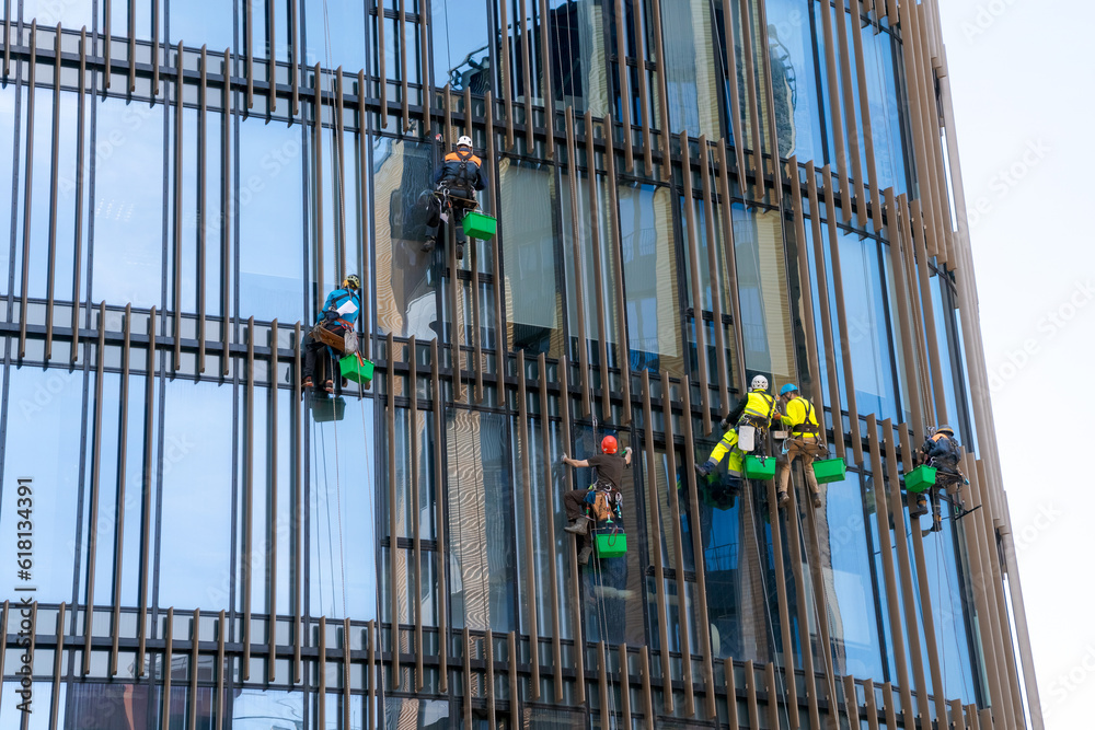 Window cleaners wash the glass of an office building at a height