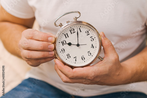 a man sets an alarm clock while sitting on the couch, close-up without a face, the concept of deadline and time control