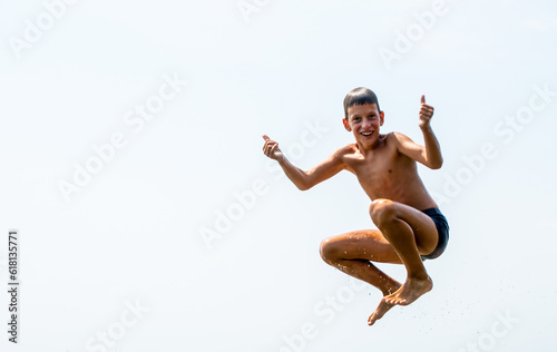 athletic teenager on the beach in jump on the background of the sky