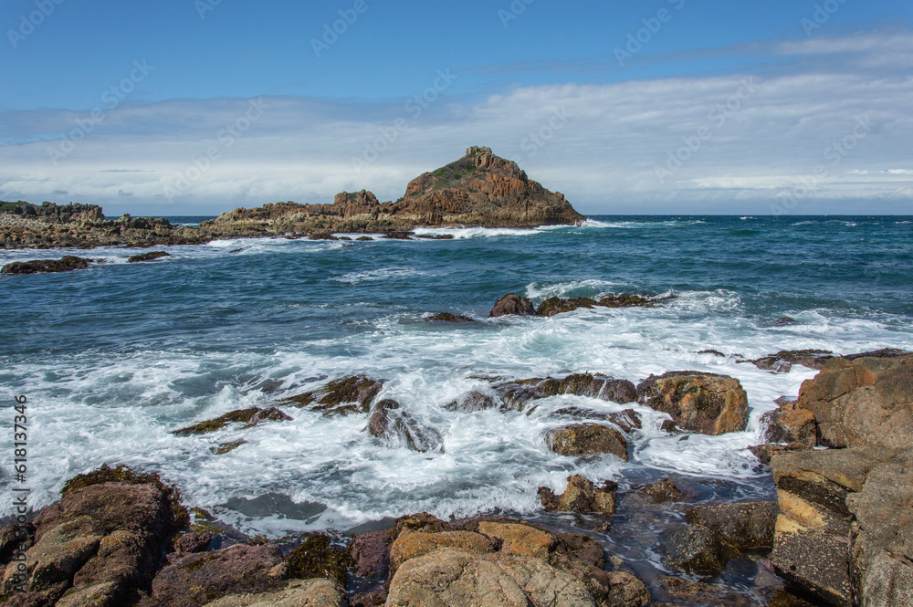 A rock formation rising from a ocean