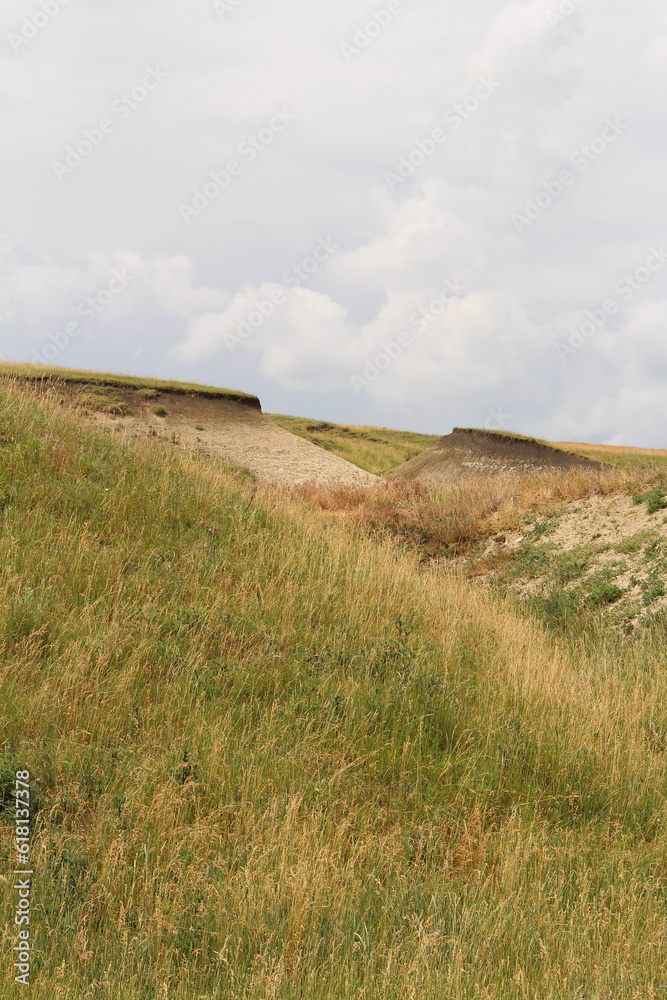 A grassy hill with a dirt path with Konza Prairie Natural Area in the background