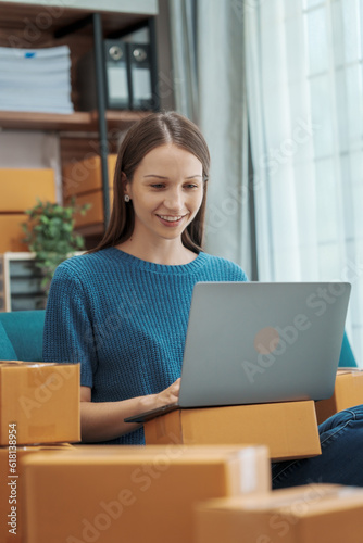 Startup small business entrepreneur SME or freelance woman using a laptop with box, Caucasian woman seller prepare parcel box of product for delivery to customer Online selling e-commerce SME concept © M+Isolation+Photo