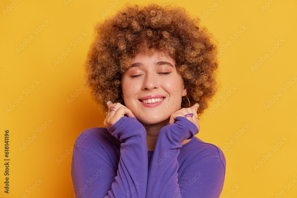 Close up portrait of young woman with Afro hairstyle wearing purple sweater, posing isolated over yellow background. Close up portrait of young woman with Afro hairstyle wearing purple sweater, posing isolated over yellow background.