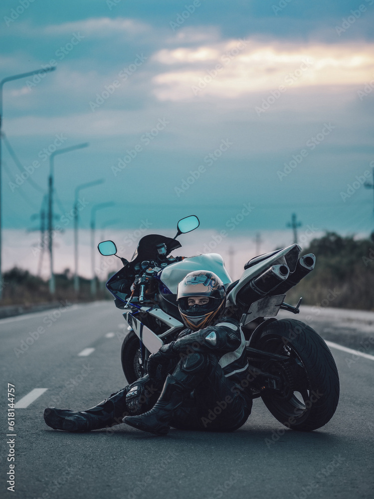 Fototapeta premium A man sits on the road near a sports bike
