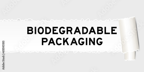 Ripped gray paper background that have word biodegradable packaging under torn part