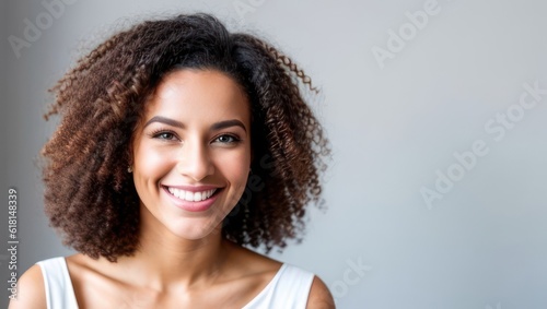 Obraz na plátne Portrait beautiful brunette model woman with white teeth smile, healthy curly hair and beauty skin on grey background