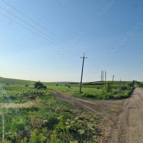 A dirt road with power lines with Codrington Wind Farm in the background
