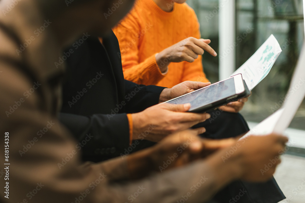 Fototapeta premium detail on hands multiracial people sitting working together on a project with sheets and tablet