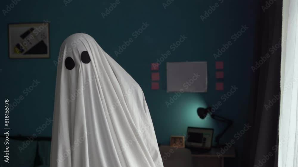 Ghost covered with a white bedsheet in the room. Halloween Concept Ghost covered with a white bedsheet in the room. Halloween Concept