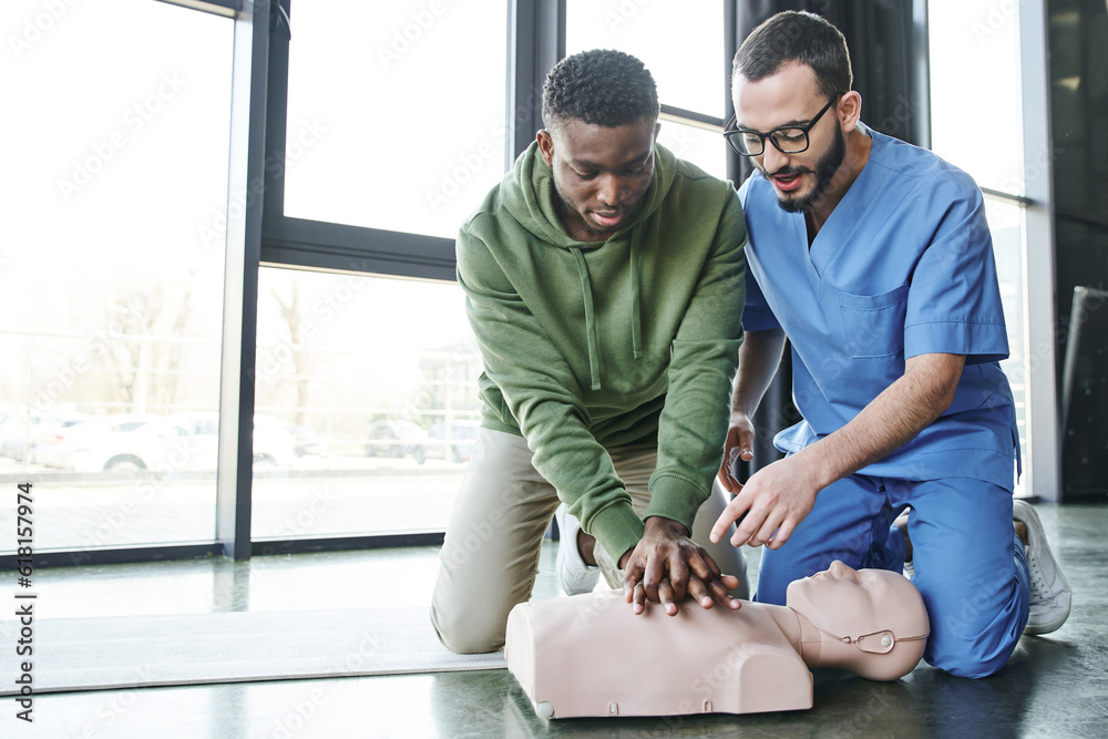 Medical Instructor medical instructor in uniform and eyeglasses pointing at CPR manikin ...