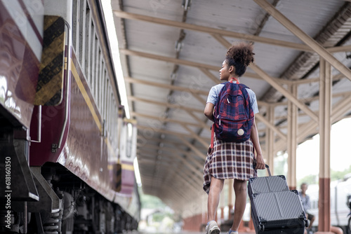 Young female traveler walking standing with a suitcase at train station. woman traveler tourist walking standing smiling with luggage at train station