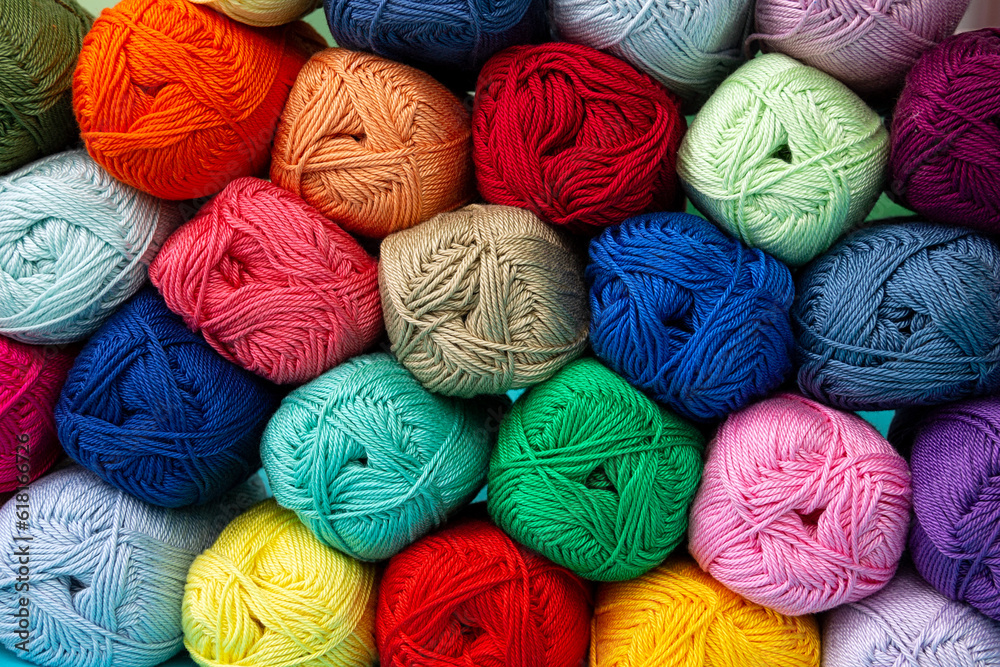 Background of multi-colored skeins of cotton yarn stacked on top of each other. Materials for knitting. Textile industry. Arranged balls of yarn. Background of multi-colored skeins of cotton yarn stacked on top of each other. Materials for knitting. Textile industry. Arranged balls of yarn.