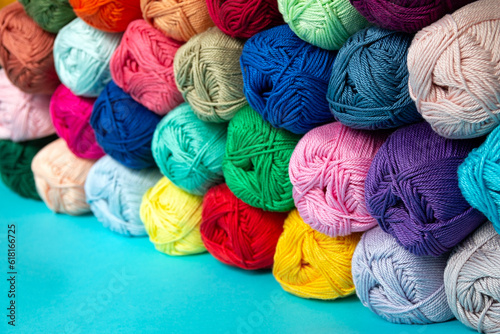 Multi-colored skeins of cotton yarn stacked on top of each other in perspective. Materials for knitting. Textile industry. Arranged balls of yarn. Small depth of field.