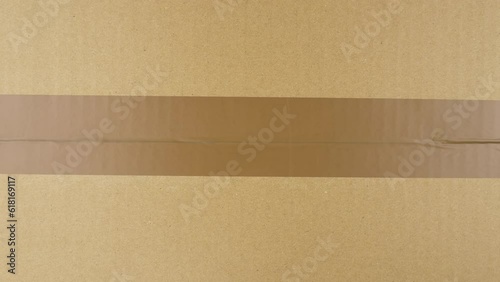 Hands sealing cardboard box with duct tape. View from top