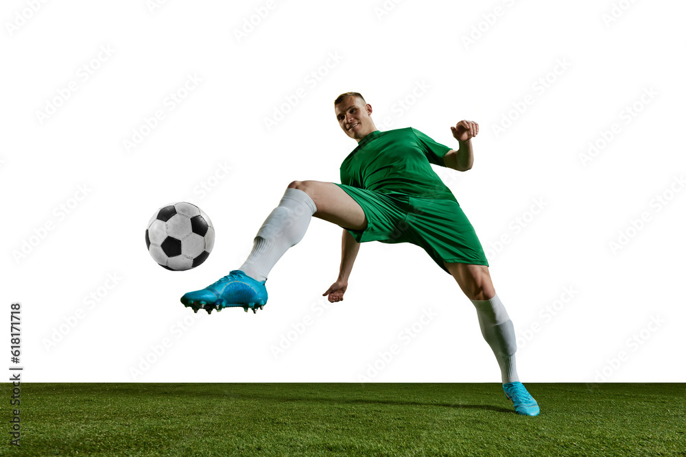 Bottom view. Competitive man, football player in green uniform kicking ball with leg against white background. Concept of professional sport, action, lifestyle, competition, hobby, training, ad