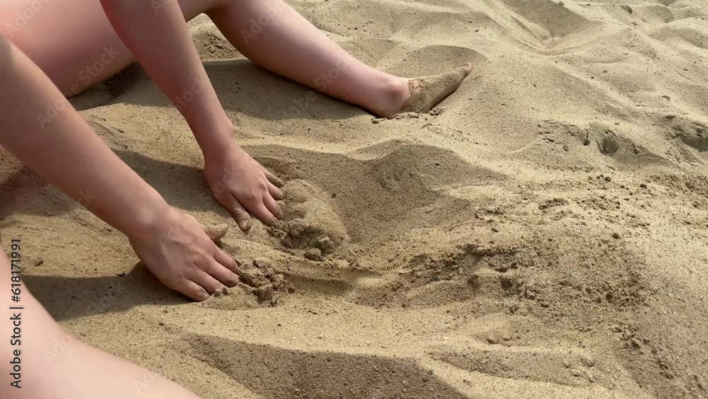 a happy child plays on the riverbank in the sand, a girl plays on the beach, builds towers and figures out of sand, the concept of a happy childhood and recreation