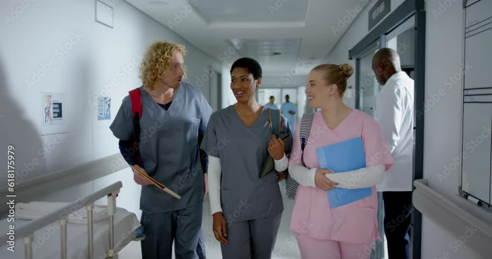 Happy diverse doctors talking and walking in corridor at hospital, slow motion Happy diverse doctors talking and walking in corridor at hospital, slow motion