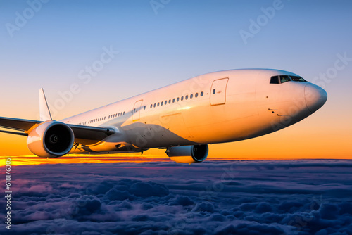 Close-up wide body passenger airplane is flying in the sunrise sky